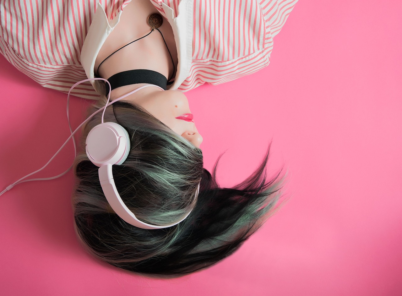 Black-haired woman on a pink background uses music for Polish total immersion.